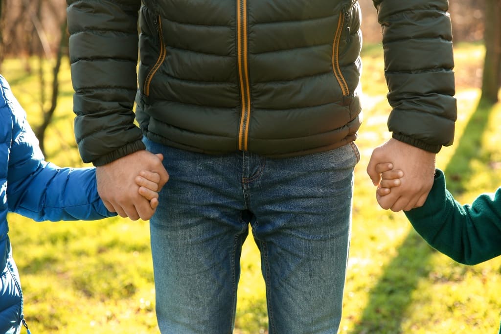 Man Holding Hands Of His Sons